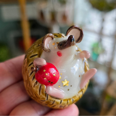 Small figurine of a hedgehog with a red ball on a blurred background