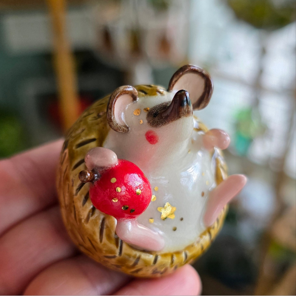 Small figurine of a hedgehog with a red ball on a blurred background
