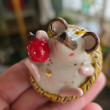 Load image into Gallery viewer, Hand holding a small ceramic animal figurine with a red berry on a blurred background